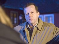 Mankells Wallander – Kommissar Wallander (Krister Henriksson) fragt sich, wie die Mitglieder der ominösen Wohngemeinschaft ein vergleichsweise komfortables Leben ohne erkennbare Erwerbstätigkeit führen können.