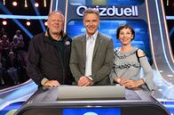 Quizduell - Olymp – Moderator Jörg Pilawa (M.) mit den Kandidaten des Teams "Tatort": Schauspieler Axel Milberg (l.) und Schauspielerin Meret Becker (r.).