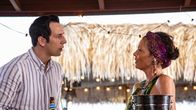 Death in Paradise – Neville Parker (Ralf Little) erkundigt sich neugierig bei der Barfrau Catherine Bordey (Elizabeth Bourgine) nach Sophie Chambers.