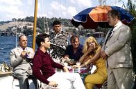 Topkapi – V.l.n.r.: Cedric (Robert Morley), Walter (Maximilian Schell), Giulio (Gilles Ségal), Hans (Jess Hahn) und Elizabeth (Melina Mercouri) gratulieren Mr. Simpson (Peter Ustinov), der erfolgreich ihre präparierte Limousine nach Istanbul eingeschleust hat.