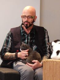 Der Katzenflüsterer – Jackson Galaxy petting a cat in the cafe with staff.