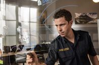 Watzmann ermittelt – Max Ruffer (Nepo Fitz) schreibt die neuesten Ermittlungsergebnisse auf die Plexiglaswand.