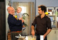 Rote Rosen – ARD ROTE ROSEN, Folge 95010 Uhr im Ersten. Nils (Gabriel Merz, r.) erzählt Alfred (Rolf Nagel, l.), der gerade auf Baby Lukas (Nicolai Saric, M.) aufpasst, dass er sich auf eine Wette eingelassen hat. Er will während des Kinderfestes als verkleideter Heiliger auftreten.