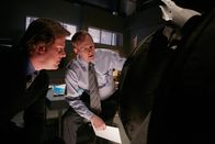 Mayday - Alarm im Cockpit – REENACTMENT - Der leitende Ermittler (gespielt von David Patrick Green) (rechts) und ein weiterer Flugunfallermittler (gespielt von einem Darsteller im Hintergrund) untersuchen ein Stück Fahrwerk, das nach dem Absturz von Atlantic Airways Flug 670 in einem Moor gefunden wurde. (Bildnachweis: Cineflix/Darren Goldstein)