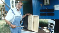 Löwenzahn Classics – Peter (Peter Lustig) baut einen Fledermaus-Nistkasten vor seinem Bauwagen.
