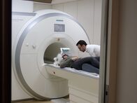 Terra Mater Wissen – Lena Hütterer liegt in der MRT-Röhre und Tibor Stöffel überprüft die Einstellungen.
