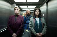 Zwei gegen die Bank – Auf dem Weg zum Showdown: Security-Mann Ari (Murathan Muslu, hi.) hat Juliette (Caroline Peters, li.) und Maggy (Daniela Golpashin, re.) geschnappt, um sie zur Bankchefin zu bringen.