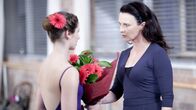 Dance Academy – Ein heimlicher Verehrer beschenkt Tara (Xenia Goodwin, l.) mit Blumen. Allerdings stellt sich raus, dass die Blumenaktionen von Kat ausgehen und einer Verkupplung dienen sollen. Miss Raine (Tara Morice, r.) empfindet dies natürlich als Störung ihrer Tanzstunde.
