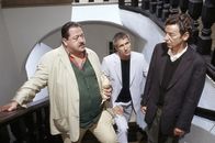 Die Rosenheim-Cops – Im Hausflur nahe beim Tatort treffen die beiden Cops Satori (Markus Böker, mi.) und Hofer (Josef Hannesschläger, li.) den Stadtarchivar Lackmeier (Michael Tregor), der seine Frau abholen wollte.