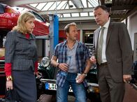 In aller Freundschaft – Roland Heilmann (Thomas Rühmann, rechts) schleppt Sarah Marquardt (Alexa Maria Surholt, links) in eine Autowerkstatt. Dort treffen sie auf den gut aussehenden Benjamin Wittenberg (Till Demtröder), den Sarah für einen Mechaniker hält. Benjamin Wittenberg hingegen, hält Roland für Sarahs Ehemann.