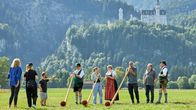 Tietjen campt - der Roadtrip – Die Gruppe versucht sich im Alphornblasen. Im Hintergrund das Schloss Neuschwanstein.