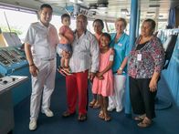 Verrückt nach Meer – Gruppenfoto auf der Brücke von Kapitän Froenenbroek, Kreuzfahrtdirektorin Manuela Bzdega und der Familie des Fischers Vai. Der Kapitän besucht mit der Kreuzfahrtdirektorin den Fischer Vai und seine Familie. Der Kapitän hat ihn zusammen mit fünf anderen Fischern 2017 mit der Albatros aus Seenot gerettet. Der Kapitän hat die Familie auf die "Grand Lady" eingeladen.