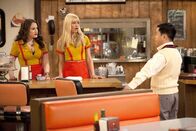 2 Broke Girls – Als Caroline (Beth Behrs, M.) mal wieder zu spät zur Arbeit kommt, wird sie von Han (Matthew Moy, r.) gefeuert. Max (Kat Dennings, l.) versucht zu vermitteln ...