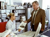 Der Bernsteinfischer – Auf einem Foto erkennt Karolines (Sonsee Neu) Chefredakteur Manfred (Michael Hanemann) die wahre Identität ihres neuen Geliebten.