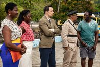 Death in Paradise – Darlene Curtis (Ginny Holder, l.), Naomi Thomas (Shantol Jackson, 2. v. l.), Detective Neville Parker (Ralf Little, M.) und der Polizeichef Selwyn Patterson (Don Warrington, 2. v. r.) stehen zusammen mit Marvin Peters (Hakeem Kae-Kazim, r.) am Strand und haben eine Überraschung für ihn vorbereitet.