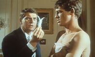 Ein Engel auf Erden – Der Rennfahrer Pierre Chaillot (Henri Vidal) verblüfft seinen Freund und Mechaniker Michel (Jean-Paul Belmondo, r) mit der Behauptung, er könnte in seinem Hotelzimmer eine Feder vom Flügel eines Engels gefunden haben.
