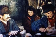 Der Graf mit der eisernen Faust – Ein kleines Mädchen erbettelt bei einem Arbeiter namens Messerstecher (Pierre Mondy, li.) und Graf Rodolphe de Sambreuil (Jean Marais, re.), der sich verkleidet als Türsteher ausgibt, etwas Brot.