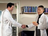 In aller Freundschaft – Dr. Philipp Brentano (Thomas Koch, links) gratuliert Dr. Kaminski (Udo Schenk) zum Herophilos-Preis für seine neueste Publikation. Kaminski ist das sichtlich peinlich.