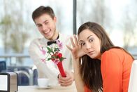 111 – Disgusted woman rejecting a geek boy offering flowers in a blind date in a coffee shop interior
