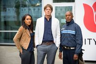 Death in Paradise – Der Polizist Humphrey (Kris Marshall, m.) ist mit seinen zwei Kollegen Dwayne (Danny John-Jules, r.) und Florence (Josephine Jobert, l.) von der Karibik nach England gereist, um einen Mordfall aufzuklären. In England ist nun eine zweite Leiche gefunden worden. Humphrey glaubt, dass die zwei Morde zusammen hängen.