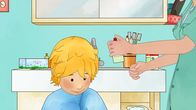 Meine Freundin Conni – Im Badezimmer sprüht Mama Conni das Anti-Läusemittel auf das trockene Haar. Conni sitzt auf einem Hocker und hat ein Handtuch um die Schulter gelegt.