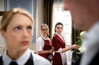 Sturm der Liebe – Josie (Lena Conzendorf, 2.v.l.) und Shirin (Merve Çakır, 2.v.r.) bekommen mit, wie sich Christoph (Dieter Bach, r.) bei Rosalie (Natalie Alison, l.) über Yvonne beschwert.