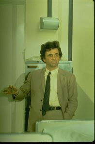 Columbo – Columbo (Peter Falk), der kultige Inspektor mit Glasauge, Trenchcoat und schräger Körperhaltung, bei seinen Recherchen.