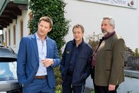 Die Rosenheim-Cops – Polizeihauptmeister Mohr (Max Müller, M.) nimmt die Kommissare Hansen (Igor Jeftic, l.) und Stadler (Dieter Fischer, r.) am Teamhotel der Biathleten in Empfang.