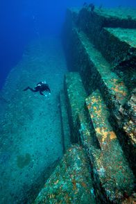 Mysteriöse Inseln – Ein Taucher untersucht die Sandsteinstruktur des unterseeischen Yonaguni-Denkmals. MYSTERIOUS ISLANDS nimmt die Zuschauer mit auf ein unvergessliches Abenteuer zur Erkundung der außergewöhnlichsten und rätselhaftesten Inseln unseres Planeten. (Kredit: MICHAEL PITTS/NATURE PICTURE LIBRARY/SCIENCE PHOTO LIBRARY)