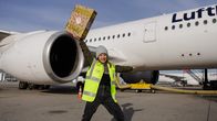 Checkerin Marina – Checkerin Marina mit einem Paket in der Hand auf dem Vorfeld des Münchner Flughafens.