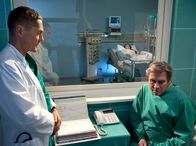 In aller Freundschaft – Dr. Kaminski (Udo Schenk, links) erklärt Alexander Nitschke (Michael Kind) warum seine Frau Ruth (Komparsin) auf der Intensivstation überwacht wird.