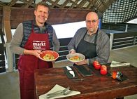 MarktFrisch – Unter dem extravaganten Dach der Markthalle in Mannheim versucht Profikoch Frank Brunswig (re.) Nicht-Koch Jens Hübschen (li.) wieder das Kochen beizubringen. Auf der Speisekarte steht dieses Mal: Doppelt paniertes Ei auf Hirse-Gemüsebeet mit Senfsoße. Und zum Nachtisch gibt es Nusstorte an Apfelkompott und Orangen-Gelee.