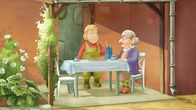 Lieselotte – Die Bäuerin und Käthe trinken Kaffee am Gartentisch.