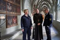 WaPo Bodensee – Paul Schott (Tim Wilde, r.) und Nele Fehrenbach (Floriane Daniel, l.) treffen Abt Barnabas (Ulrich Gebauer, M.) im Kreuzgang von Kloster Oberzell.