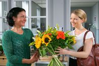 Die Rosenheim-Cops – Noch glaubt Controllerin Ortmann (Diana Staehly, r.), dass der Blumenstrauß für sie bestimmt ist. Sekretärin Stockl (Marisa Burger, l.) freut sich mit ihr.