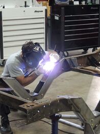 Fast N' Loud – Aaron Kaufman, wearing a large head light, works on the fram of the 1976 Chevy Silverado C-10.