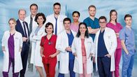 In aller Freundschaft - Die jungen Ärzte – v.l.n.r. hintere Reihe: Horst Günter Marx als Wolfgang Berger, Christian Beermann als Dr. Marc Lindner, Mike Adler als Dr. Matteo Moreau, Elisa Agbaglah als Dr. Emma Jahn, Luan Gummich als Mikko Rantala, Isabella Krieger als Viktoria Stadler, Lion Wasczyk als Florian Osterwald. vordere Reihe: Mirka Pigulla als Dr. Julia Berger, Marijam Agischewa als Prof. Dr. Karin Patzelt, Milena Straube als Rebecca Krieger, Philipp Danne als Dr. Ben Ahlbeck, Sanam Afrashteh als Dr. Leyla Sherbaz, Stefan Ruppe als Dr. Elias Bähr. Copyright: SRF/ARD