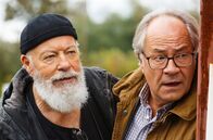 Rentnercops – Reinhard Bielefelder (Bill Mockridge, l.) und Klaus Schmitz (Hartmut Volle, r.) beobachten aus einem Versteck heraus Naumann, der offensichtlich in Schwierigkeiten steckt.