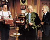 Brust oder Keule – Während Charles (Louis de Funès, m.) mit seinem privaten Schneider (Marcel Dalio, r.) scherzt, versucht Gérard (Coluche, l.) seiner Angebeteten Marguerite mit einem Präsent zu schmeicheln.