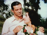 Elefantenpfad – Ruth Wiley (Elizabeth Taylor, r.) fühlt sich von Dick Carver (Dana Andrews, l.) unwiderstehlich angezogen, doch sie ist mit seinem Chef verheiratet ...