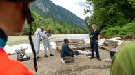 Watzmann ermittelt – Caro Reisser (Sarah Thonig, r.) teilt Jerry Paulsen (Peter Marton, M.) die Todesursache und den Todeszeitpunkt des Opfers mit (mit Kompars:innen).