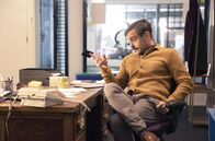 Guilt - Keiner ist schuld – Kenny (Emun Elliott) beobachtet Max, der gerade einige Unterlagen durchgeht, und fragt ihn, was es damit auf sich hat.