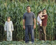 Signs - Zeichen – Fassungslos stehen (v.l.n.r.) Morgan (Rory Culkin), Graham (Mel Gibson), Bo (Abigail Breslin) und Merrill (Joaquin Phoenix) vor den rätselhaften Kornkreisen, die er auf seinem Feld entdeckt. Noch während er die Übeltäter in seiner näheren Umgebung sucht, tauchen weltweit ähnliche Phänomene auf ...