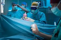 In aller Freundschaft – Dr. Ilay Demir (Tan Caglar, re.) musste als Assistenzarzt der Neurochirurgie die OP schon beginnen, während Dr. Schmidt (Eric Schnerr, li.) aus unerklärlichen Gründen mit seiner Schlüsselkarte nicht in den OP kam. Nun ist er da und wird übernehmen. Ilay hat damit seinen Kompetenzbereich weit überschritten.