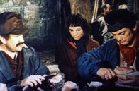 Der Graf mit der eisernen Faust – Ein kleines Mädchen erbettelt bei einem Arbeiter namens Messerstecher (Pierre Mondy, li.) und Graf Rodolphe de Sambreuil (Jean Marais, re.), der sich verkleidet als Türsteher ausgibt, etwas Brot.
