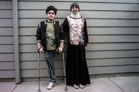 Es war einmal im Irak – Student Mustafa Ahmed Abed (li.) in Begleitung von Um Mustafa Nidhal (re.). Mustafa erlitt als Kleinkind schwerste Verletzungen bei einem der frühen Luftangriffe auf Falludscha im November 2004.