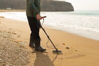 Treasure Hunters Down Under – A man with a metal detector and a shovel on the seashore. A treasure hunter with a metal detector. A man is looking for a treasure. metal detector close-up.