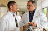 In aller Freundschaft – Dr. Kaminski (Udo Schenk, li.) verlangt von seinem ihm zugeteilten Assistenzarzt Hans-Peter Brenner (Michael Trischan, re.) keine Alleingänge und ständigen Rapport. Und dass dieser ständig mit den Patienten "schwatzt", geht Kaminski eh auf die Nerven. Doch Hans-Peter stellt richtig: Er redet mit ihnen und hört zu. Das ist ein großer Unterschied.