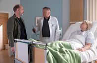 In aller Freundschaft – Als Dr. Roland Heilmann (Thomas Rühmann, mi.) nach seiner Patientin Stefanie Vollinger (Susanna Simon, re.) sehen will, ist diese grad in einer lautstarken Auseinandersetzung mit ihrem Mann Silvi0 (Martin Ontrop, li.). Da Stefanie eine wirklich schwere Operation hinter sich hat, bittet Roland ihren Mann zu gehen.