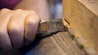 Handwerkskunst! – Hier nietet Gerd Fritsche die Seitenteile und die Hobelsohle zusammen. Er schlägt auf die herausragenden Zinken der Hobelsohle und drückt das Material so in die Hinterschneidungen der Schwalbenschwänze.